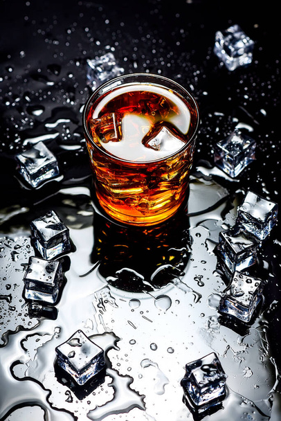 Whisky met ijsblokjes op zwarte ondergrond van bovenaf.Glas whisky en ijsblokjes op een zwarte ondergrond - Foto, afbeelding