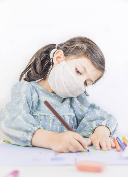 Petite fille étudiant et dessinant à la maison ou à l'école avec un masque. Coronavirus. Covid 19
 - Photo, image