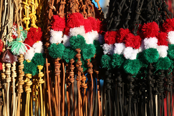 Tradycyjne skórzane bicze na sprzedaż w węgierskich kolorach narodowych. Poziome zdjęcie. Czerwone białe i zielone kolorowe węgierskie bicze na rynku rolnym na sprzedaż - Zdjęcie, obraz