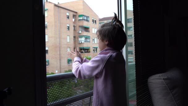 Κορίτσι χειροκροτεί στο παράθυρο για να υποστηρίξει τους ανθρώπους κατά του coronavirus - Πλάνα, βίντεο