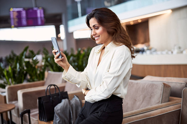 Smiling pretty lady using mobile phone at business center - Foto, imagen