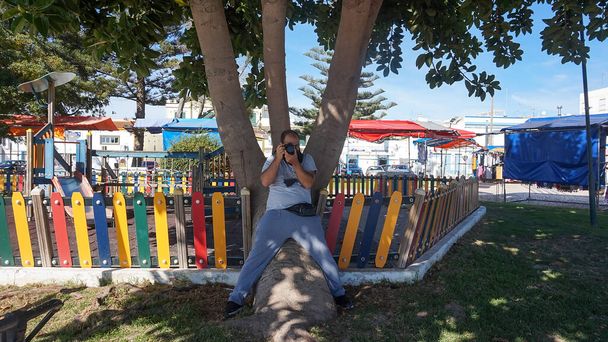 fotógrafo sentado en un árbol en un parque infantil
 - Foto, Imagen