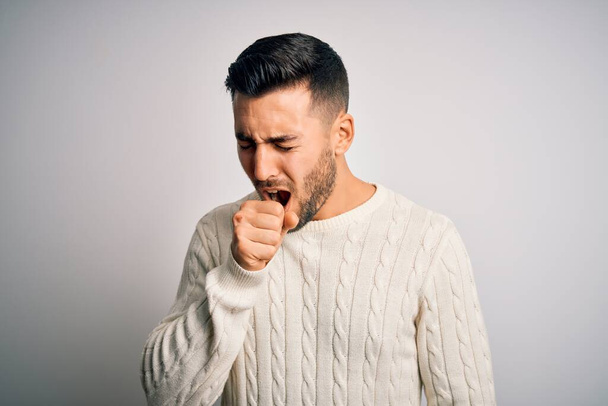 Young handsome man wearing casual sweater standing over isolated white background feeling unwell and coughing as symptom for cold or bronchitis. Health care concept. - Photo, Image