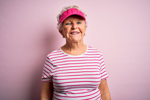 Senior bella donna sportiva indossa berretto sportivo in piedi su sfondo rosa isolato con un sorriso felice e fresco sul viso. Persona fortunato
. - Foto, immagini