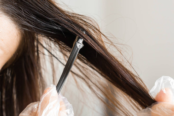 Fechar as mãos mulher tingir o cabelo usando uma escova preta. Coloração de cabelos brancos em casa
.. - Foto, Imagem