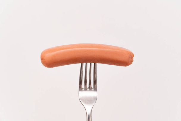 Raw frankfurter sausage on a fork isolated  - 写真・画像