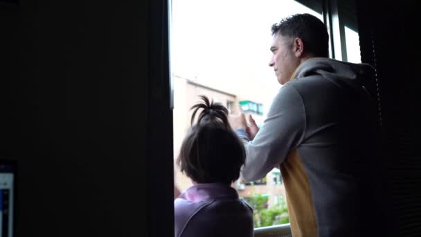 Padre e hija aplaudiendo en la ventana en apoyo de la gente contra el coronavirus
 - Metraje, vídeo