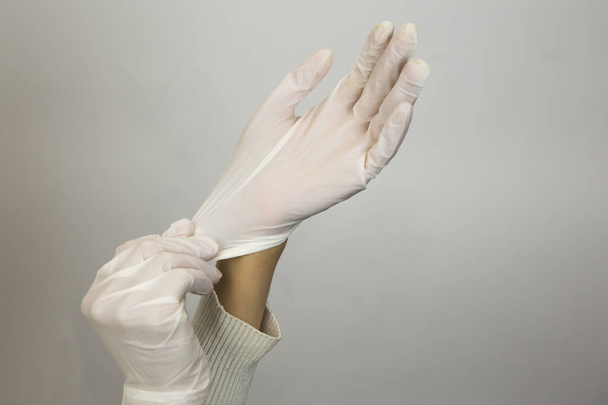 Mains féminines portant des gants en latex sur fond blanc
 - Photo, image