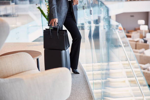Señora con el equipaje de pie en el segundo piso de la zona de espera del aeropuerto
 - Foto, imagen