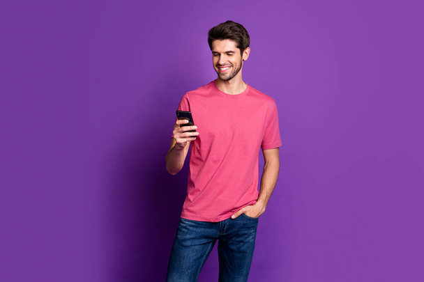 Portrait of positive cheerful guy use cell phone enjoy chatting repost share social network information wear style stylish trendy outfit isolated over bright shine color background - Foto, Bild