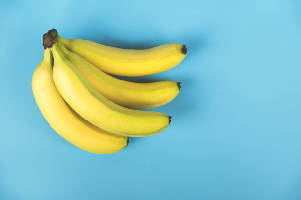 Bright bunch of bananas on a blue background - Valokuva, kuva