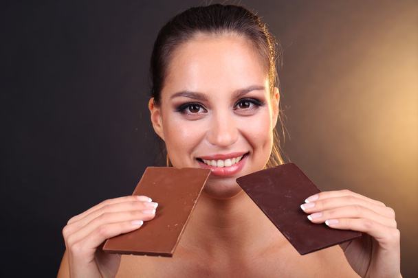 Portrait of beautiful young girl with chocolate on brown background - Fotoğraf, Görsel