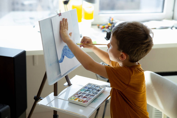 Cute little boy painting picture on easel - Φωτογραφία, εικόνα