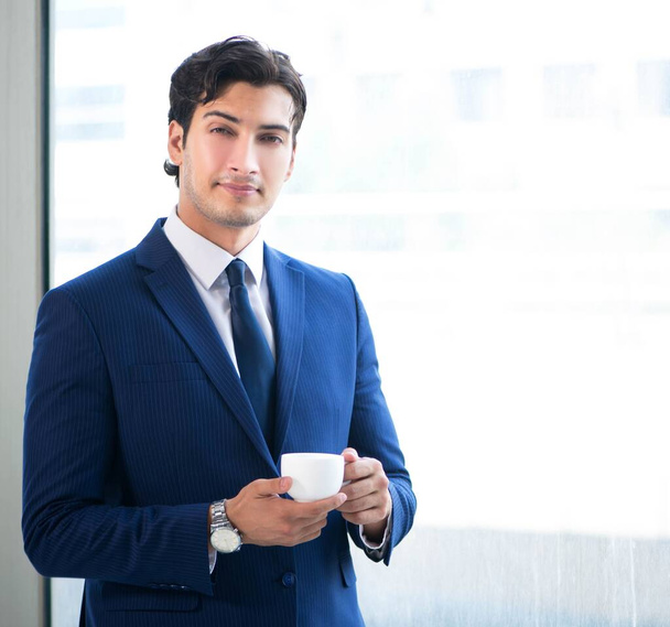 Молодой привлекательный бизнесмен стоит у окна
 - Фото, изображение