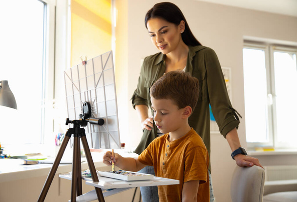 Cute little boy painting picture and spending time with mother - Foto, Bild