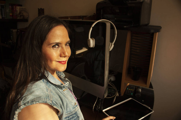 Lächelnde Frau, die von zu Hause aus mit Technologie an ihren Fingerspitzen aus der Ferne arbeitet - Foto, Bild