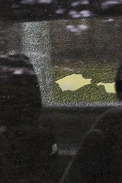 verbrijzeld glas van een autoraam dat wordt verplaatst met een zwarte handschoen - Foto, afbeelding