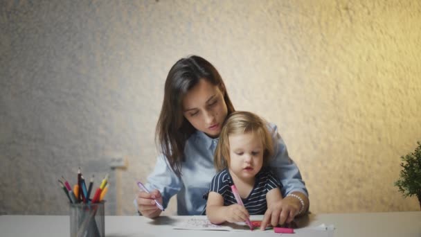 Νεαρή μητέρα και κόρη ζωγραφίζουν χρωματιστά μολύβια μαζί. Παιδικά χόμπι δημιουργική εκπαίδευση έννοια - Πλάνα, βίντεο