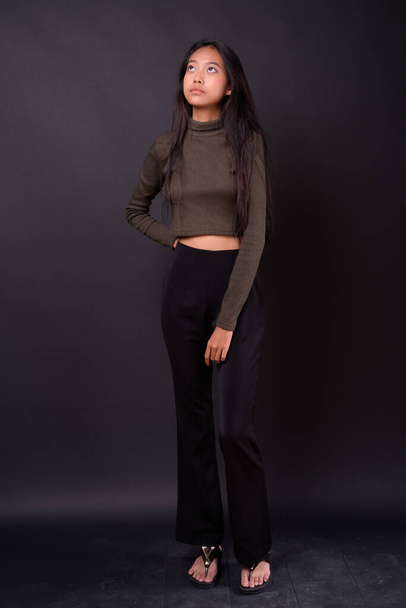 Studio colpo di giovane bella donna asiatica che indossa maglione dolcevita contro sfondo nero - Foto, immagini