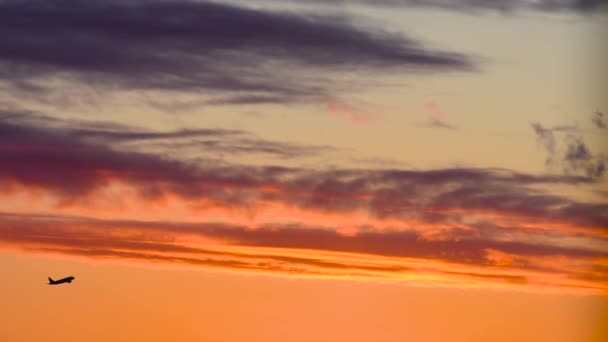 Gün batımı gökyüzü parlak turuncu ve uçak silueti havaalanından kalkıyor. - Video, Çekim