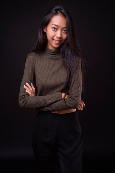 Estudio disparo de joven hermosa mujer asiática con jersey de cuello alto sobre fondo negro - Foto, imagen