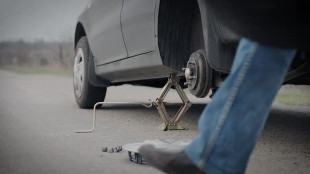montáž náhradní pneumatiky člověkem uprostřed silnice - Záběry, video