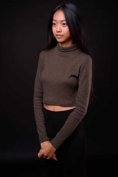 Stúdió lövés fiatal gyönyörű ázsiai nő visel garbó pulóver ellen fekete háttér - Fotó, kép