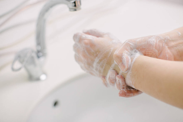 Femme se lave les mains par méthode chirurgicale de lavage des mains. Elle lui lave les mains pendant au moins 20 secondes. Elle se lave les poignets. Elle se lave les mains pour la protéger de Covid-19
. - Photo, image