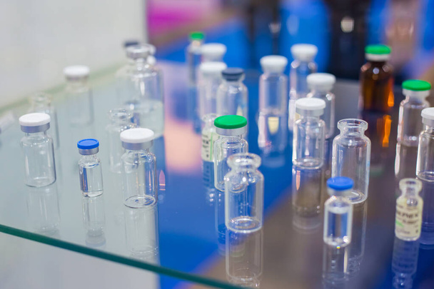 Медицинские пустые стеклянные бутылки в витрине фармацевтической выставки
 - Фото, изображение