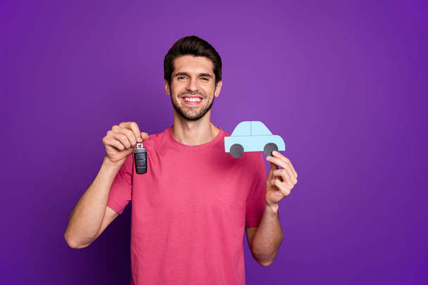 Photo of attractive handsome guy good mood hold paper blue car hands dealer agent offer keys credit percent money wear casual pink t-shirt isolated purple color background - Фото, зображення
