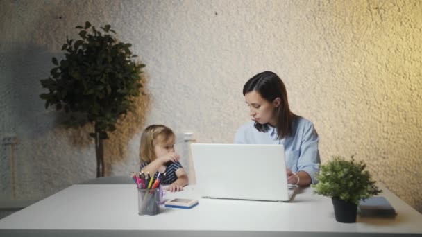 Der Anblick des kleinen Mädchens lenkt die Mutter von der Arbeit ab. Geschäftsfrau arbeitet mit Baby im Büro am Laptop - Filmmaterial, Video