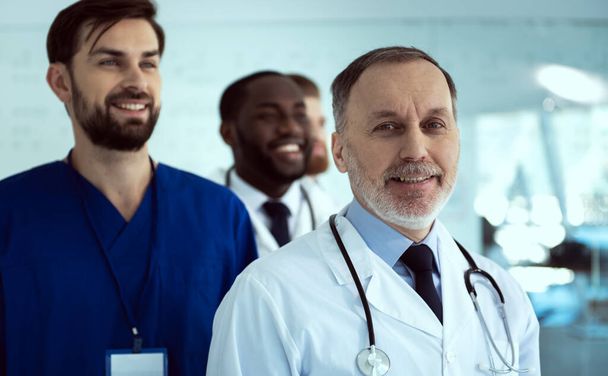 Joyful doctor and his colleagues standing in hospital - Фото, зображення