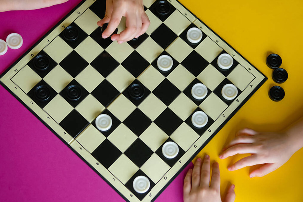 I bambini giocano a dama su un tavolo colorato. Ragazzo e una ragazza competono in giochi da tavolo. Vista dall'alto
. - Foto, immagini