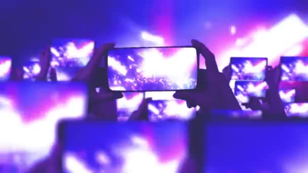 The crowd watches a concert, sings, jumps. Gold confetti floating in the air during a concert. Fans are recording videos on smartphones. A lot of smartphones. Live Stream. Stories. Strobing stage light. - Footage, Video
