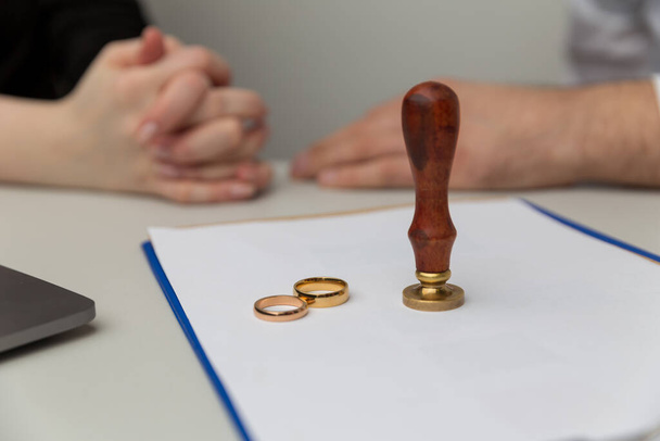 Boşanma işlemi devam ediyor. Kadın ve erkek belgeleri imzalıyor. Evlilik yüzükleri masada.. - Fotoğraf, Görsel