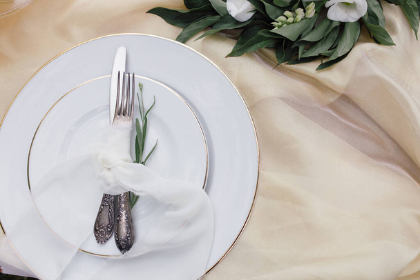 Knife, white plate and fork on beige background - Valokuva, kuva