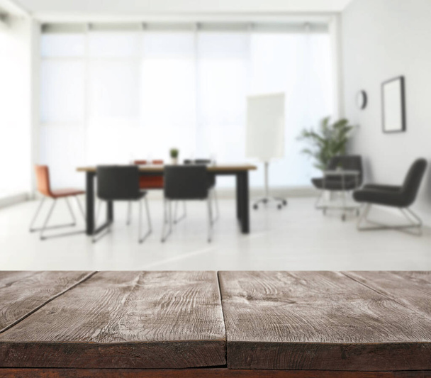 Empty wooden surface and blurred view of modern office interior, closeup. Space for text  - 写真・画像