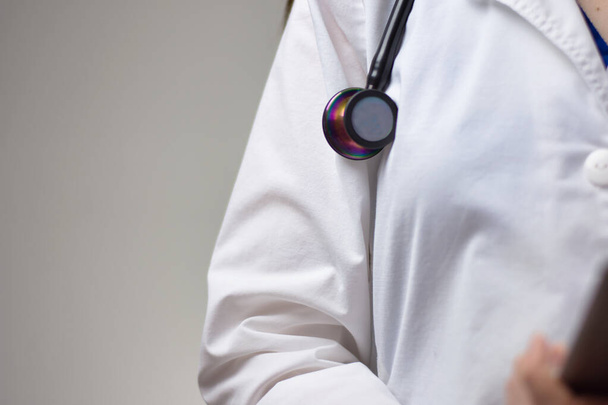 Zblízka stetoskop na bílém plášti ženského zdravotnického pracovníka. Izolováno na šedém pozadí. - Fotografie, Obrázek