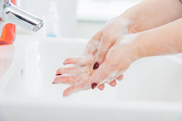 石鹸で手を洗う若い女性の切り取られたショット。コロナウイルス保護の概念 - 写真・画像