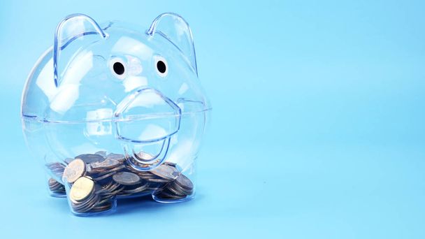 Glazen spaarvarken op blauwe achtergrond financieel concept, Bespaar geld en het kweken van geld - Foto, afbeelding
