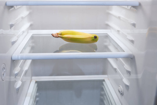 Bananas in an empty refrigerator. Symbol of poverty. Hungry life concept - 写真・画像