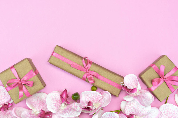 litteä-lay lahja laatikot vaaleanpunainen nauha vaaleanpunainen tausta orkidea kukkia ylhäältä näkymä. Lahja tai läsnä keväällä käsite. Kopioi tila
 - Valokuva, kuva