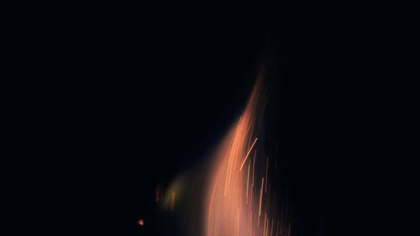 Makrofoto von Bonfire funks. Feuerflammen lodern, lodern. Explosionsartige Mikrofunkeln. Mini-Feuerwerk. Dreharbeiten auf roter Kamera noch auf schwarzem Hintergrund. Schöne Lecks überlagern Funken. - Foto, Bild