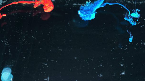 Makro-Fotoshooting mit bunter Tinte im Wasser. Macht magische mehrfarbige Unterwasserfarbe Tropfen Hintergrund. Rote Kamera noch Plakatkulisse. Schöne Tapete. - Foto, Bild