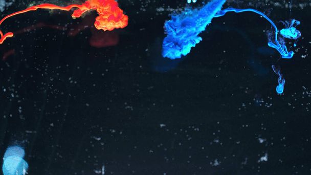 Makro-Fotoshooting mit bunter Tinte im Wasser. Macht magische mehrfarbige Unterwasserfarbe Tropfen Hintergrund. Rote Kamera noch Plakatkulisse. Schöne Tapete. - Foto, Bild