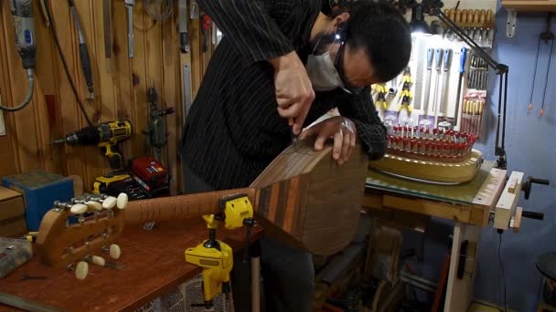 ein Mann schneidet ein quadratisches Loch von der Seite des Instruments für eine Equalizer-Montage ab - Filmmaterial, Video
