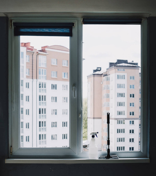 Καθαριστικό παραθύρων και ψεκασμός βούρτσας για παράθυρα κοντά στο παράθυρο. Φως ημέρας - Φωτογραφία, εικόνα
