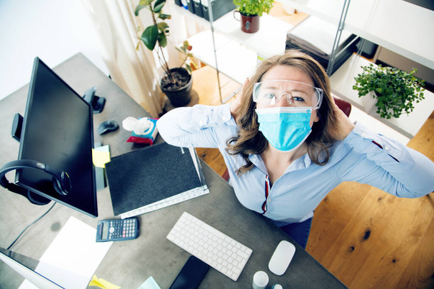 young woman in medical mask working from home during coronavirus quarantine - Фото, изображение
