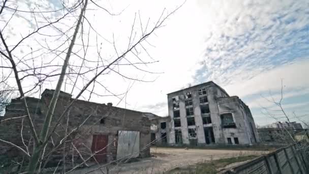 Een verlaten plek met verwoeste lege gebouwen buiten. Grijze verlaten gebouwen zonder ramen na militaire acties. - Video