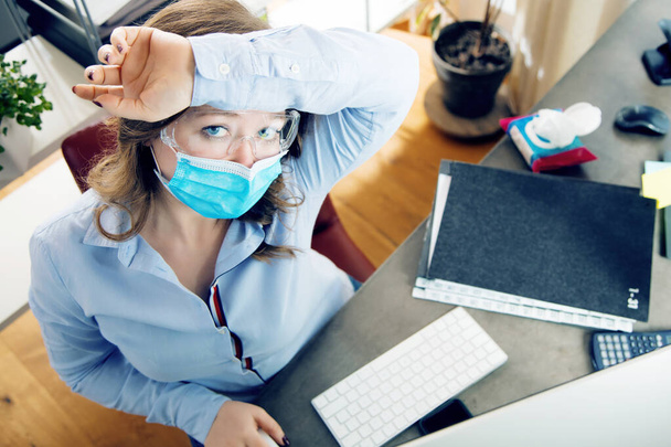 молода жінка в медичній масці працює з дому під час карантину
 - Фото, зображення